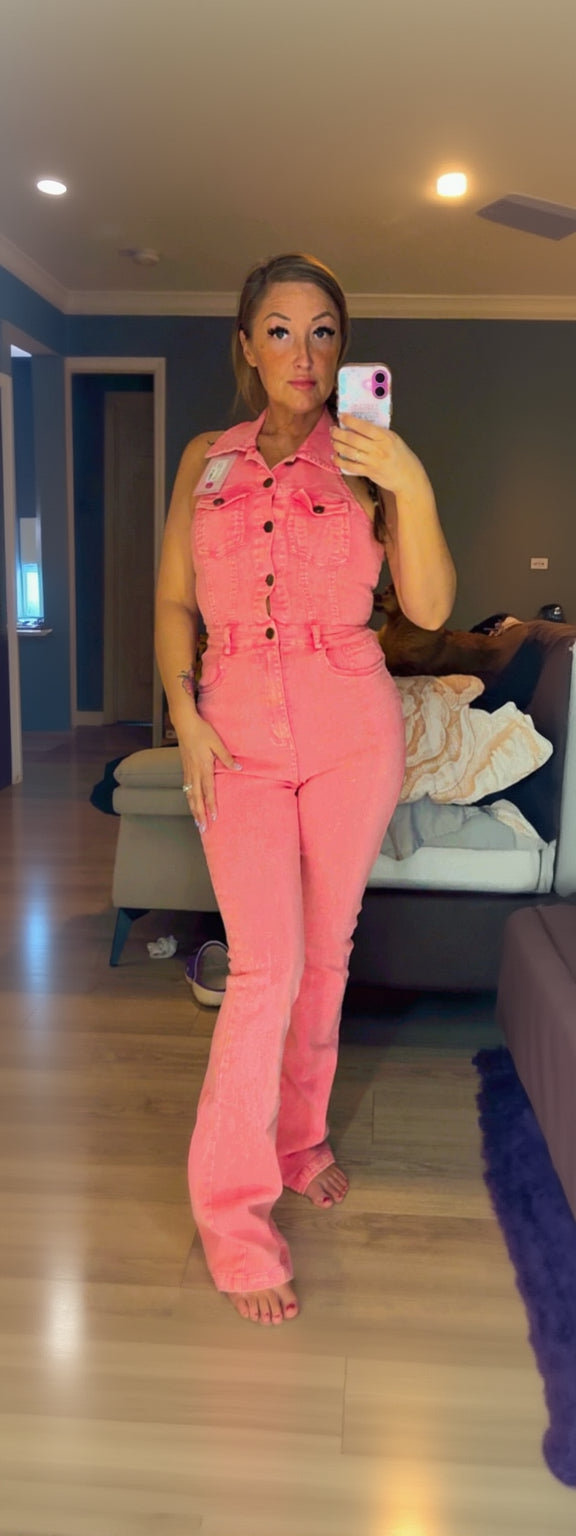 Person wearing a pink jumpsuit taking a mirror selfie in a room.