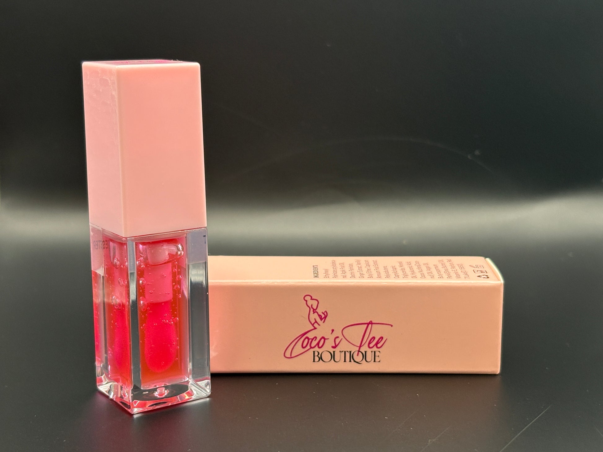 Red lip gloss with pink packaging on a black background, featuring 'Coco's Tee Boutique' branding.