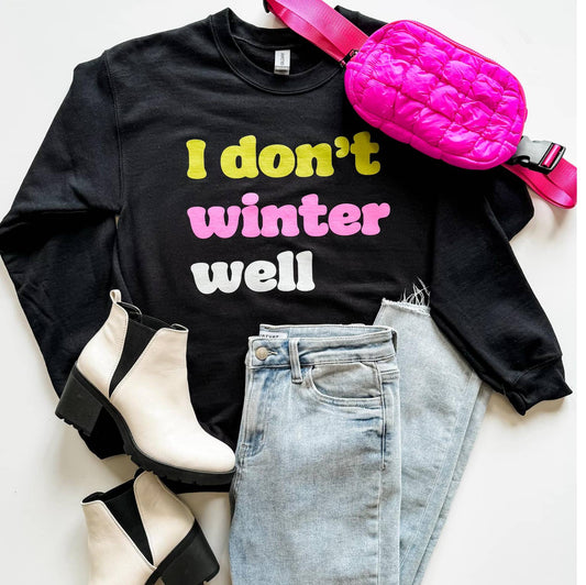 Black sweatshirt with colorful text, pink bag, jeans, and boots on a light background